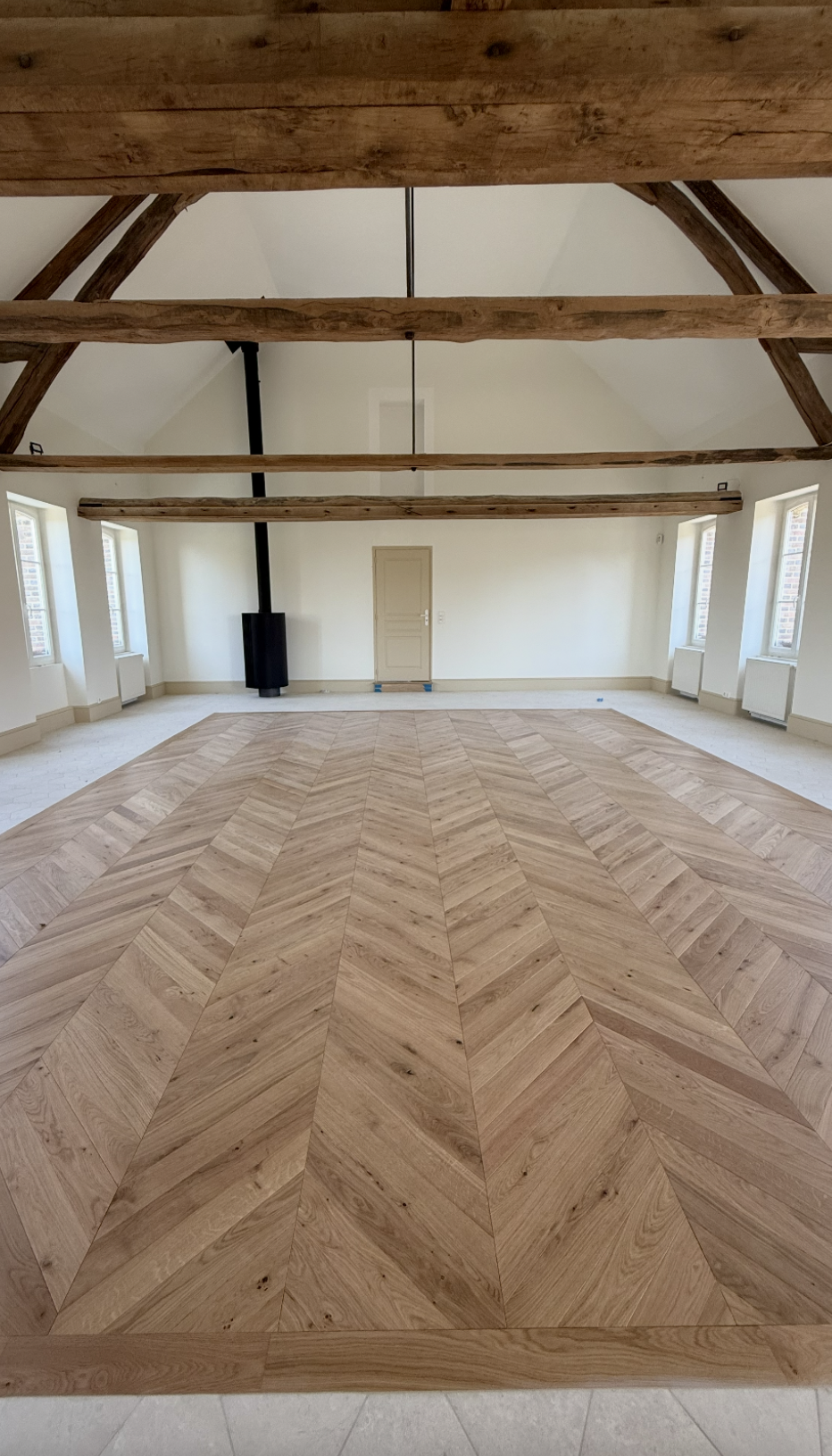 Aménagement d’un salon dans une maison à Volgré avec parquet en chevrons et poutres apparentes – projet JBB Architecture par Jean-Baptiste Brulé