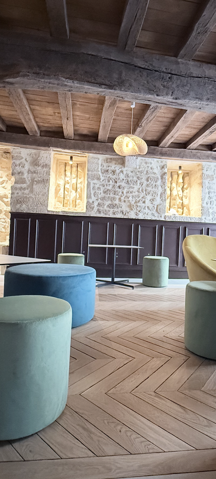 Aménagement intérieur dans l’ancienne prison de Chablis, murs en pierre apparente, plafond poutres bois et parquet chêne en pose chevrons – JBB Architecture